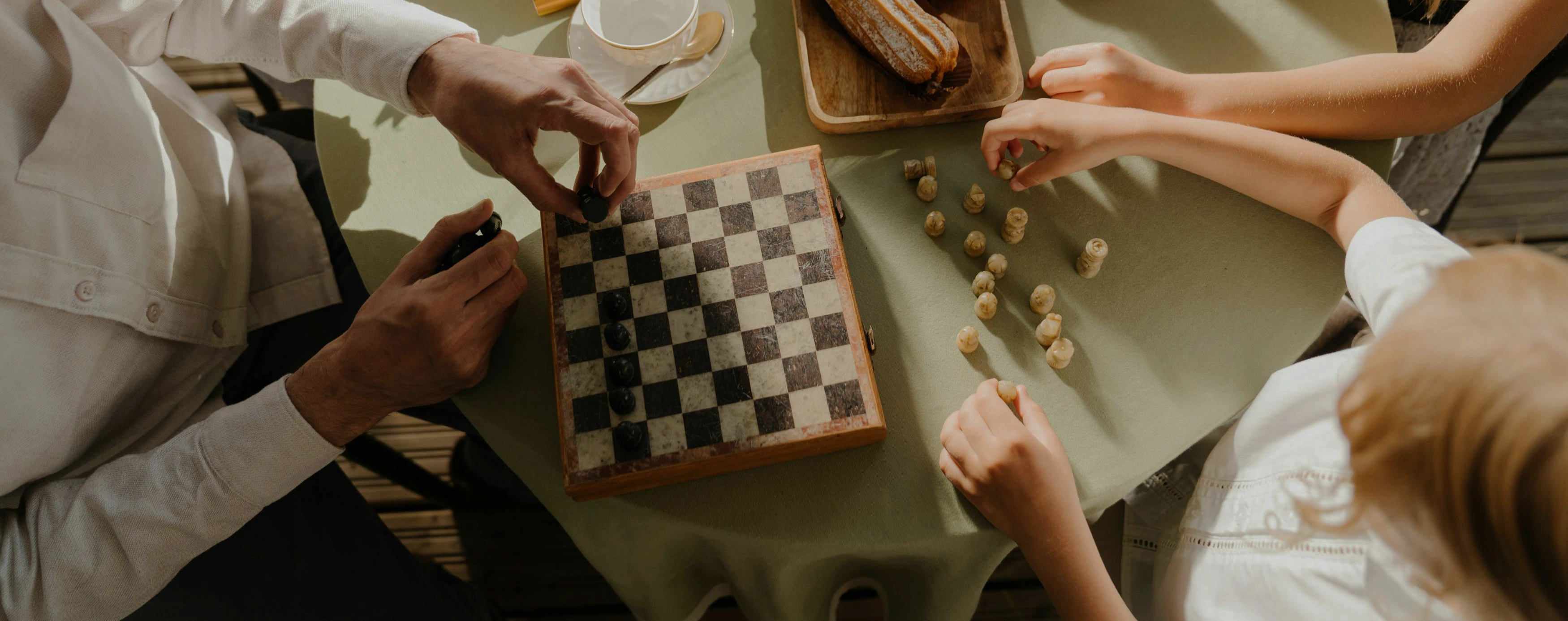 Familie sitzt gemeinasam am Frühstückstisch und spielt Schach.