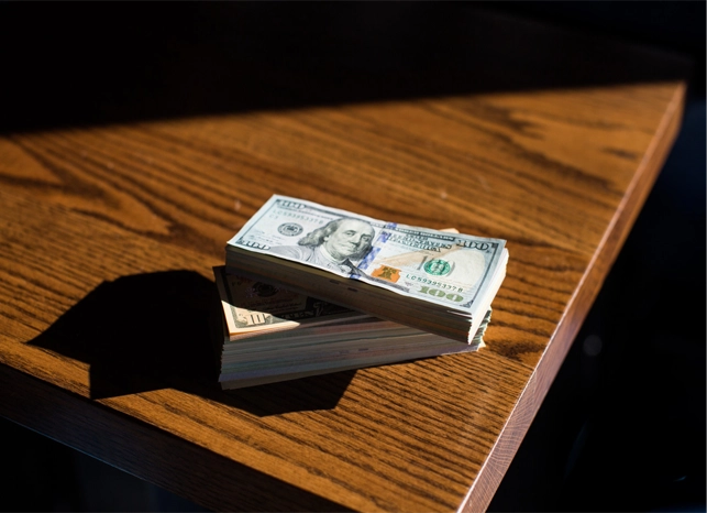 Stacked dollar bills on a wooden table