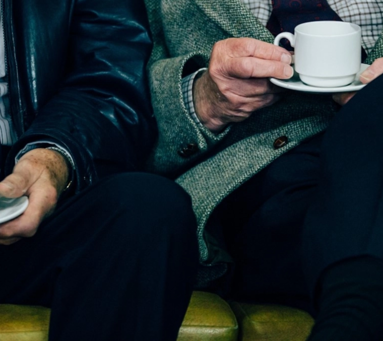 Zwei ältere Männer in Anzügen trinken Kaffee